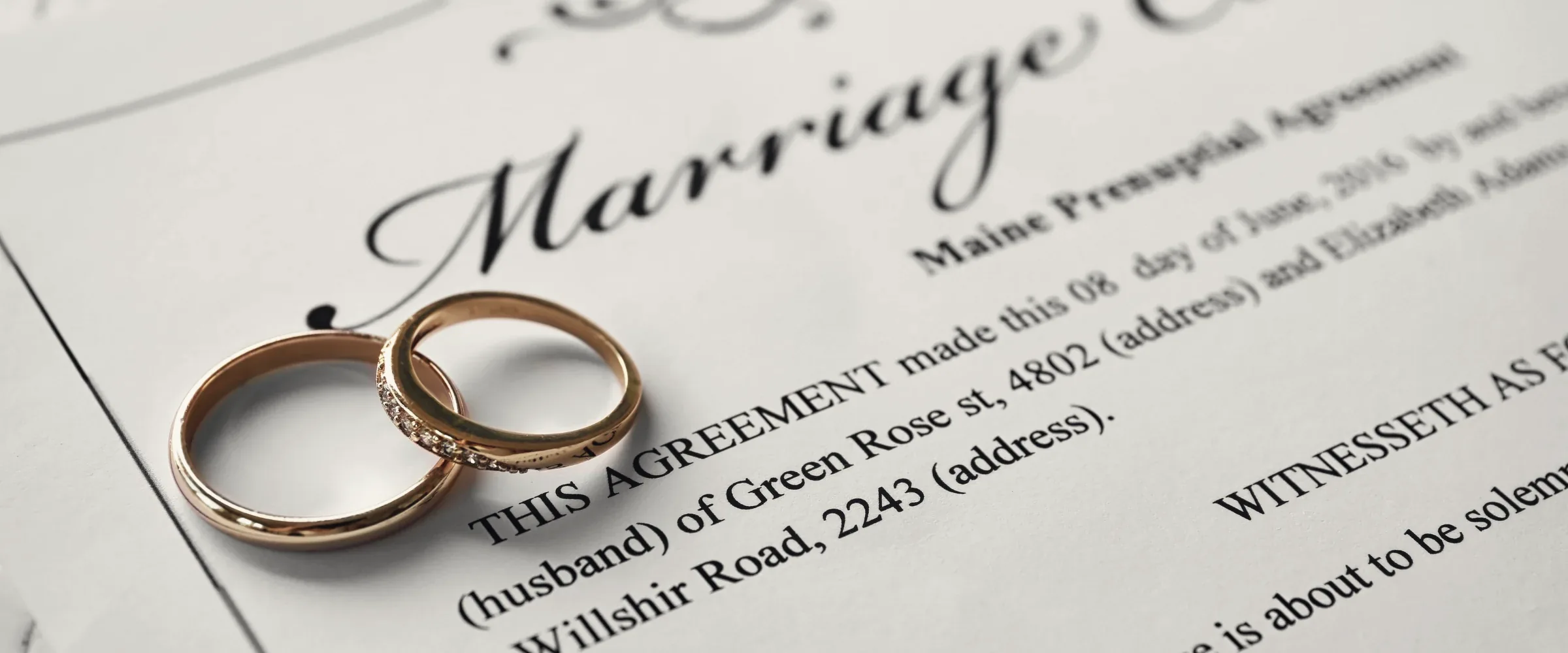 Wedding documents, rings and a pen laid out on linen